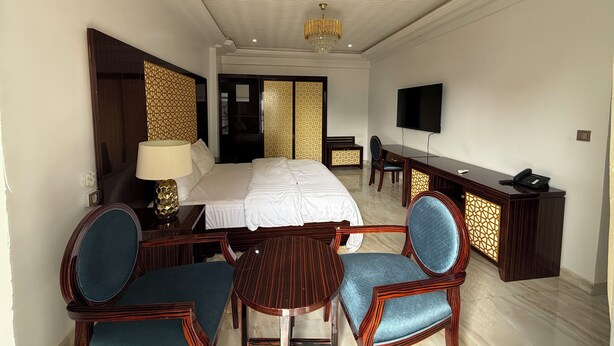 Een hotelkamer met een bed, een bureau, twee stoelen, een televisie en een telefoon.