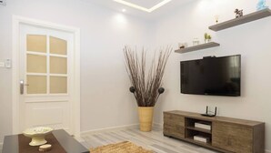 Un saló modern amb televisió de pantalla plana, una consola de fusta i plantes decoratives.