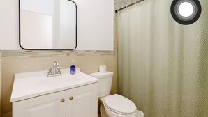 A bathroom with a white sink, a mirror, a toilet, and a shower curtain. - Miami Beach Quaint Studio  (Miami Beach)
