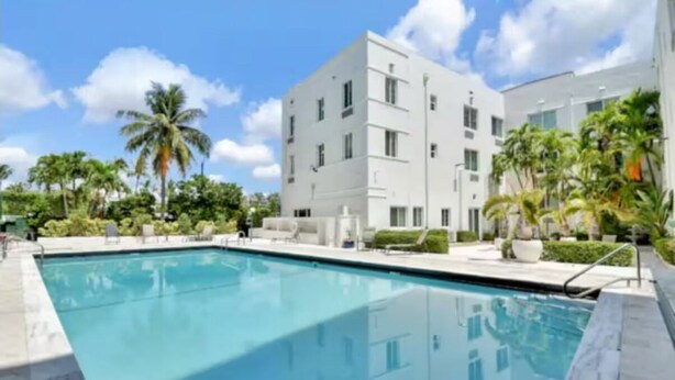 A modern building with a pool, surrounded by palm trees and greenery. - Miami Beach Quaint Studio  (Miami Beach)