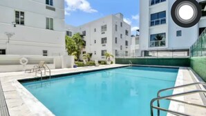 A swimming pool with a metal ladder and a small deck area. - Miami Beach Quaint Studio  (Miami Beach)