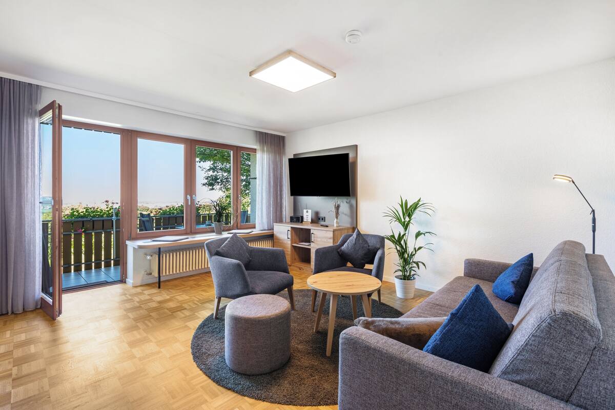 A modern living room with a sofa, chairs, a coffee table, and a TV.