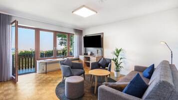 Una sala de estar moderna con un sofá, sillas, una mesa de centro y un televisor.