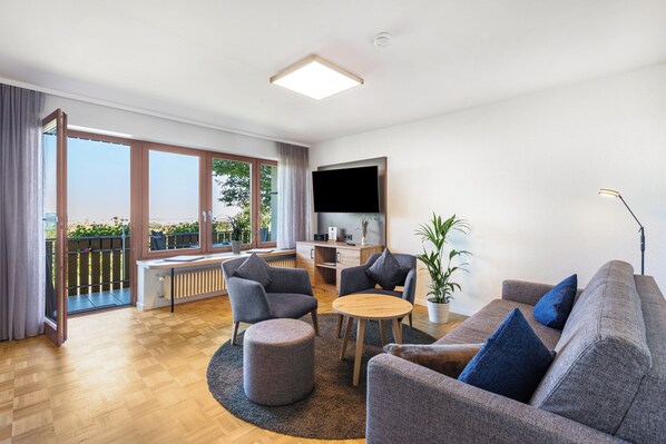 A modern living room with a sofa, chairs, a coffee table, and a TV. - Pappelhof Ferienwohnungen (Bad Bellingen)