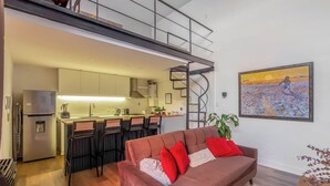 A modern apartment with a kitchen, a dining area, and a living room with a sofa and a painting. - RARE Designer Loft w/ Garden, Jacuzzi & Rooftop! (DAI)