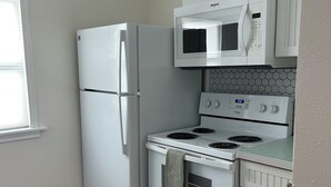 Eine Küche mit weißem Kühlschrank, Mikrowelle, Herd und Backofen.
