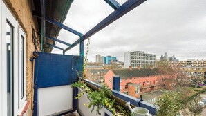 A balcony with a view of a cityscape, including buildings and a clear sky. - 1 Bedroom flat in Trendy East London (London)