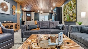 A modern living room with a gray sectional sofa, a wooden coffee table, and a wall-mounted green moss wall. - Evergreen Escape - Luxury Rooftop - Indoor Pool - Home Theater - Game Rooms (Sevierville)