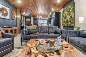Ein modernes Wohnzimmer mit einem grauen Ecksofa, einem Holztisch und einer grünen Wand aus Moos, die an der Wand befestigt ist.
