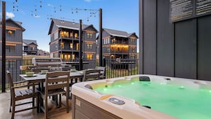 A hot tub in a backyard with a dining area and a grill. - Evergreen Escape - Luxury Rooftop - Indoor Pool - Home Theater - Game Rooms (Sevierville)