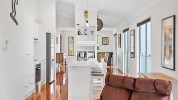 A modern kitchen with white cabinetry, a central island, and a dining area with a brown upholstered chair.