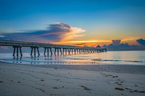 Un muelle se adentra en aguas tranquilas, con un atardecer de fondo.