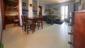 Un salon spacieux avec un coin repas, une cuisine dotée de meubles en bois et une grande plante en pot.