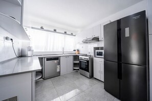 A modern kitchen with stainless steel appliances, including a refrigerator, oven, and dishwasher. - 4BD House • Pool • Heart of Herzliya by SeaNRent (Herzliya)