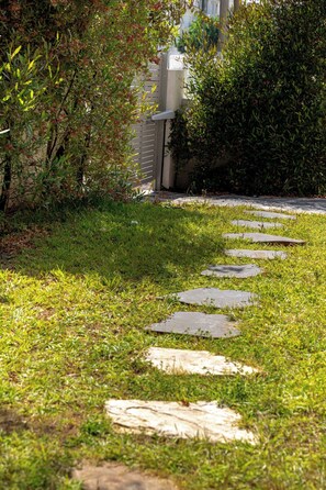 A pathway with stepping stones leading through a grassy area with dense shrubbery on either side. - 4BD House • Pool • Heart of Herzliya by SeaNRent (Herzliya)