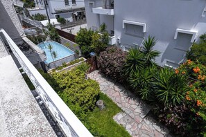 Un edificio residencial con piscina, sendero de piedra y diversas plantas.