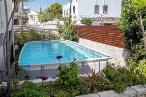 Une piscine rectangulaire à l’eau d’un bleu limpide, entourée d’un mur de pierre et agrémentée de diverses plantes.