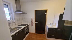 Een kleine keuken met een spoelbak, fornuis en kastjes.