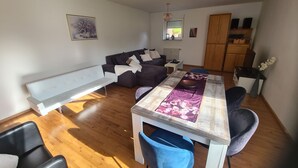 Een moderne woonkamer met een witte bank, een donkere bank en een eettafel met stoelen.