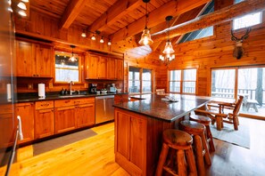 L’intérieur d’une cabane en bois comprend une cuisine, un coin repas et de grandes fenêtres.