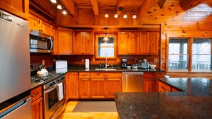 A wooden cabin-style kitchen with a refrigerator, stove, oven, microwave, and sink.
