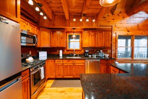 Une cuisine de style rustique, avec des éléments en bois, comprenant un réfrigérateur, une cuisinière, un four, un four à micro-ondes et un évier.