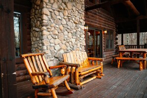Eine Holzterrasse mit einer Steinmauer, Holzbanken und einem Tisch.