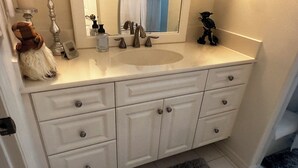 Een badkamer met een wit wastafelmeubel, een spiegel, een wastafel en een klein decoratief object op het aanrecht.