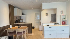 Cocina compacta con comedor, muebles blancos y un botiquín en la encimera.