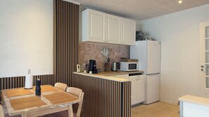 Una cocina compacta con una mesa de comedor, un microondas, una cafetera y un refrigerador.