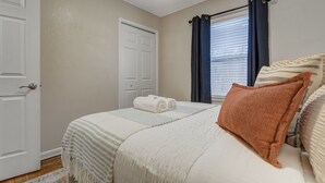 Une chambre à coucher avec un lit, une fenêtre avec des rideaux, une porte et un tapis.