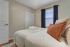 A bedroom with a bed, a window with curtains, a door, and a rug. - 5BR Group Home by the Olympic Center / Hot Tub, 2 Kitchens (Colorado Springs)