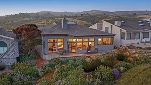 A modern house with large windows, a deck, and a garden with various plants. - Pacific Flyaway, by Vinifera Homes (Bodega Bay)