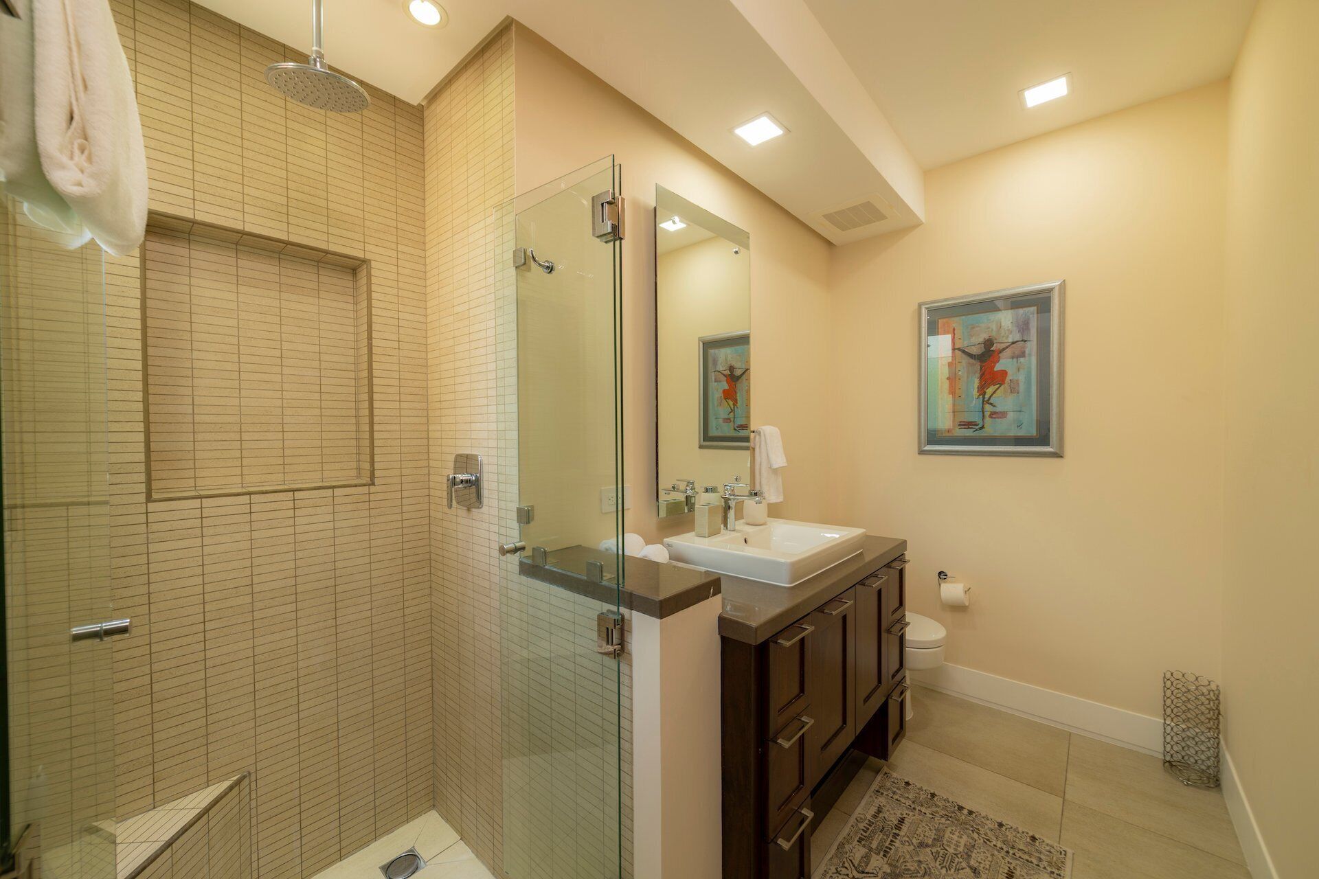 A modern bathroom with a glass shower enclosure, a sink with a mirror, and a toilet.
