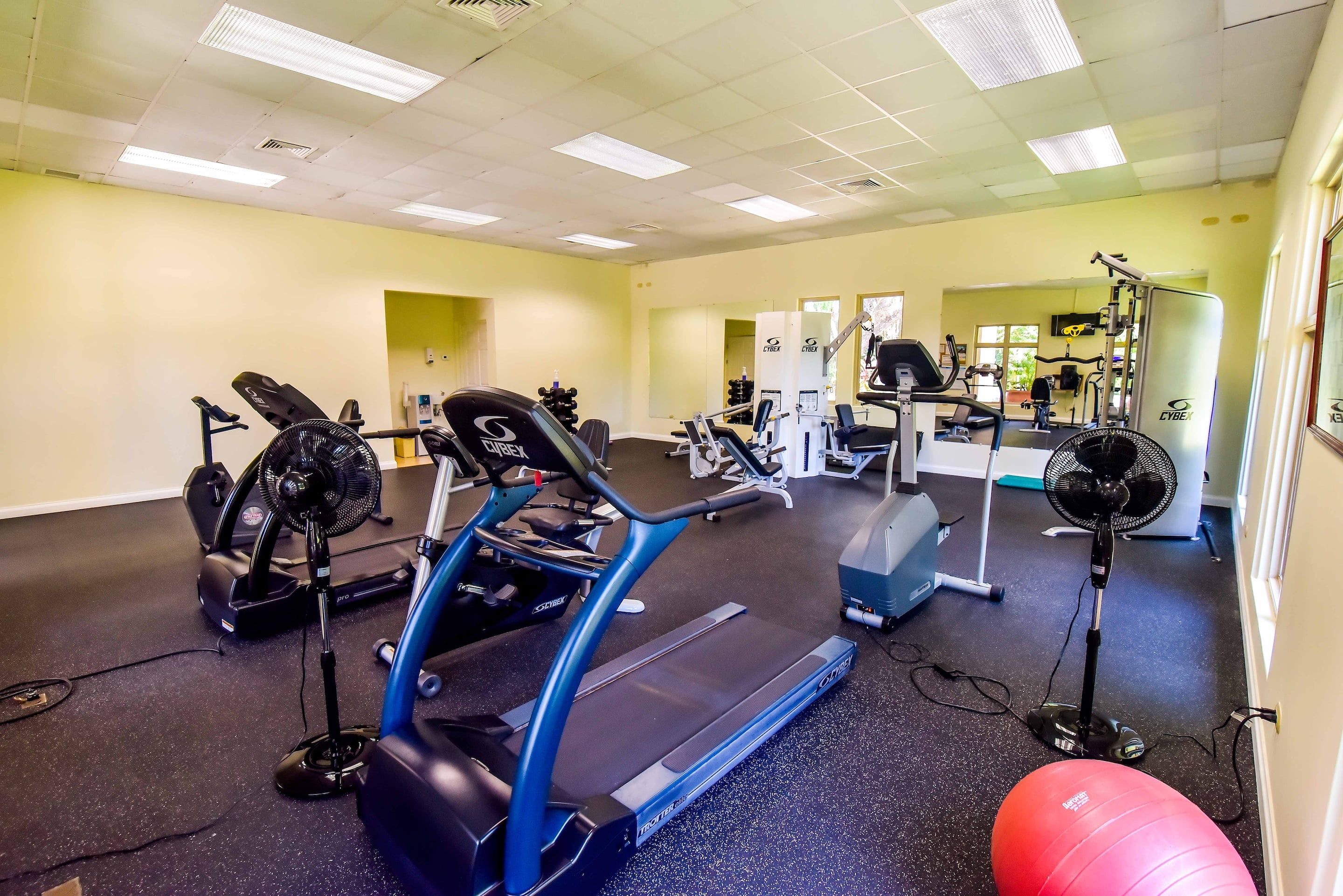 A gym with cardio equipment, weights, and a mirrored wall.