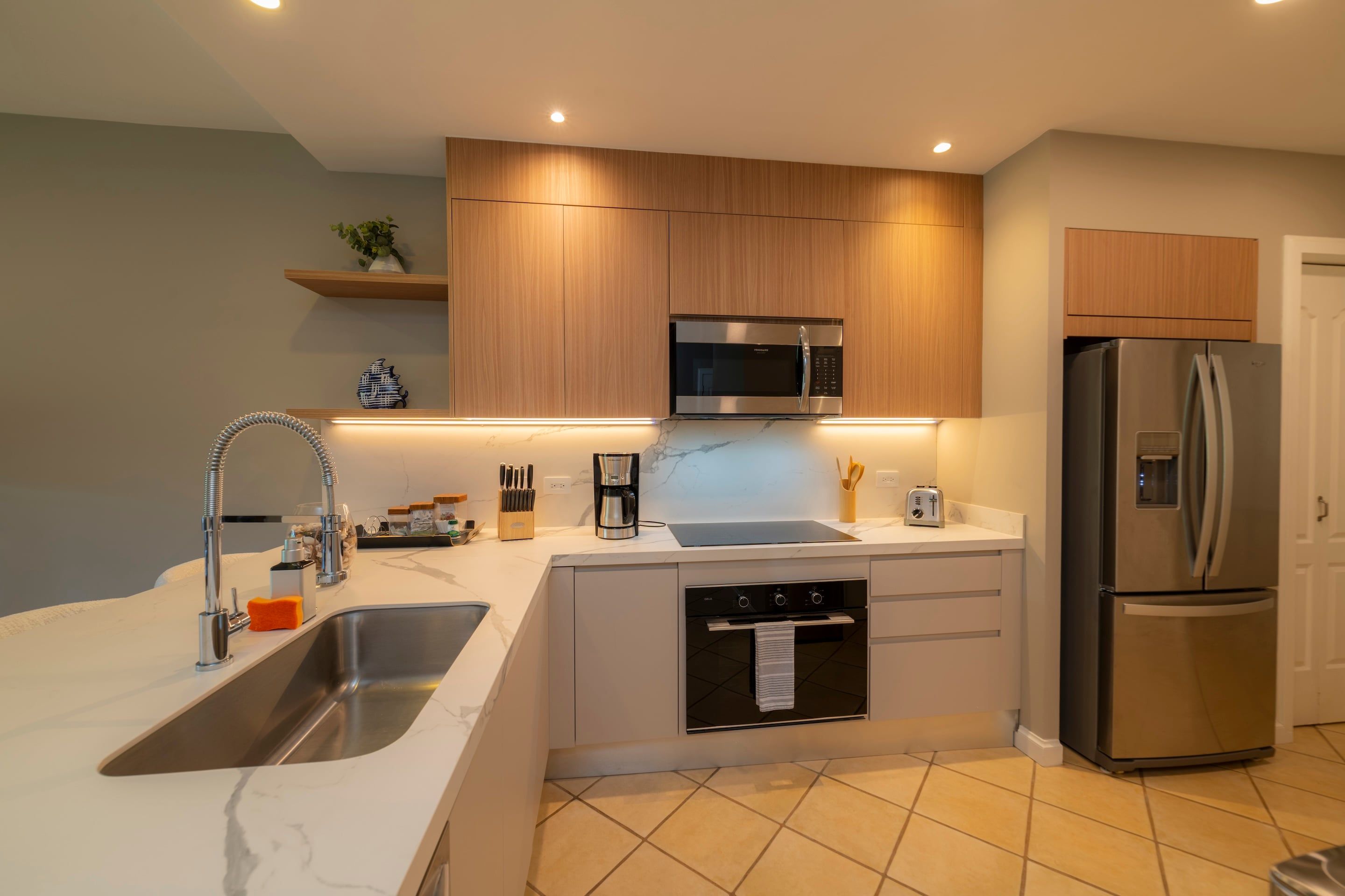 A modern kitchen with a built-in microwave, stainless steel refrigerator, and a sink with a faucet.