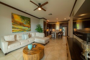 A modern living room with a sectional sofa, a coffee table, and a large abstract painting. - AltaVista 4B 3 bdr Ocean View in Los Suenos (Herradura)
