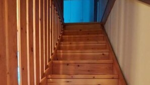 Un escalier en bois, doté d’une rampe, mène à une pièce dont un des murs est bleu.