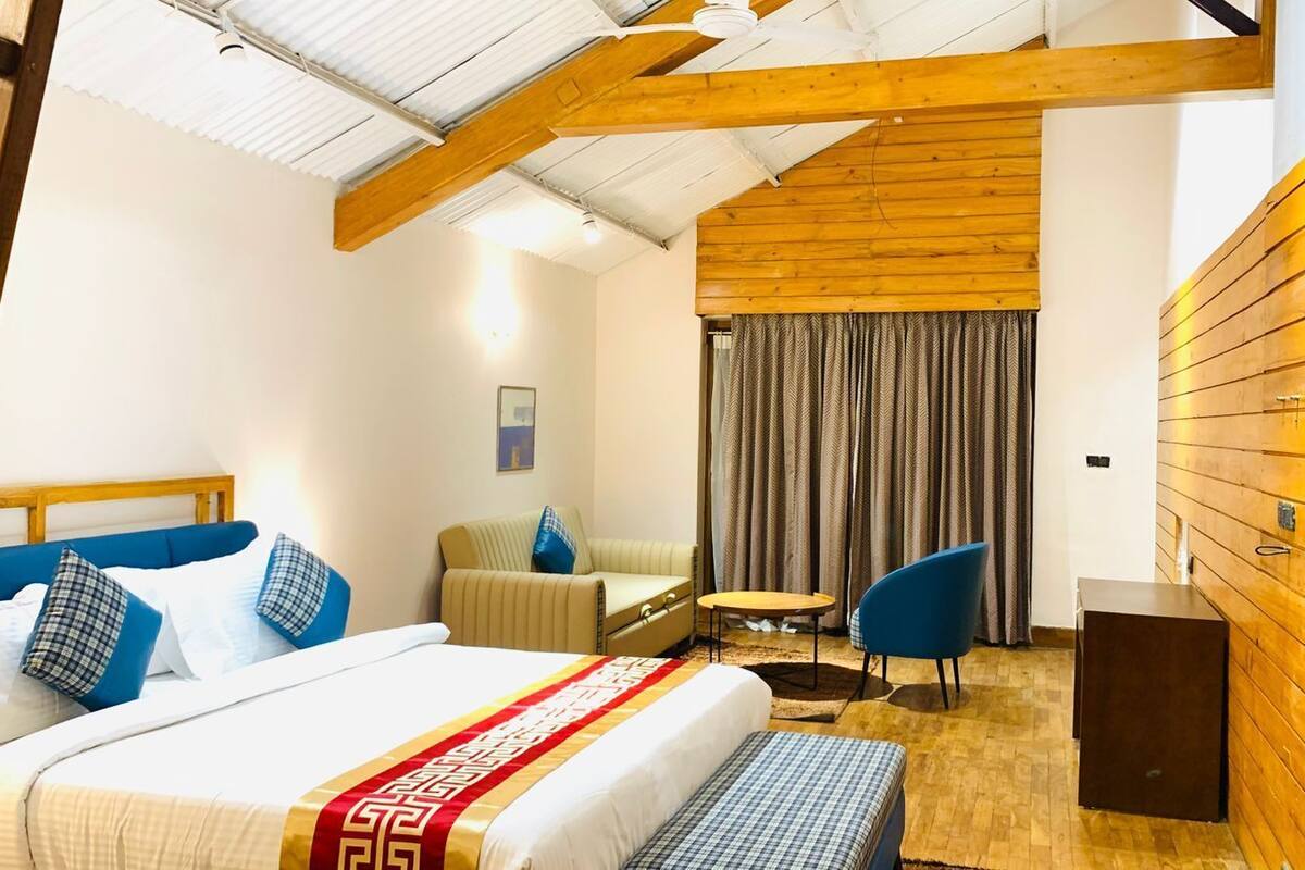 A hotel room with a bed, a sofa, a small table, and a wooden wall.