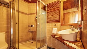 A bathroom with a glass-enclosed shower, a white sink, and wooden cabinetry.