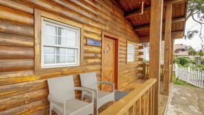 Une cabane en rondins avec une véranda, deux fauteuils en osier et une porte portant le numéro « 4001 ».