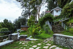 A stone staircase leading to a wooden cabin, surrounded by lush greenery and a clear sky. - The Mainland Resorts Kodaikanal (Kodaikanal)