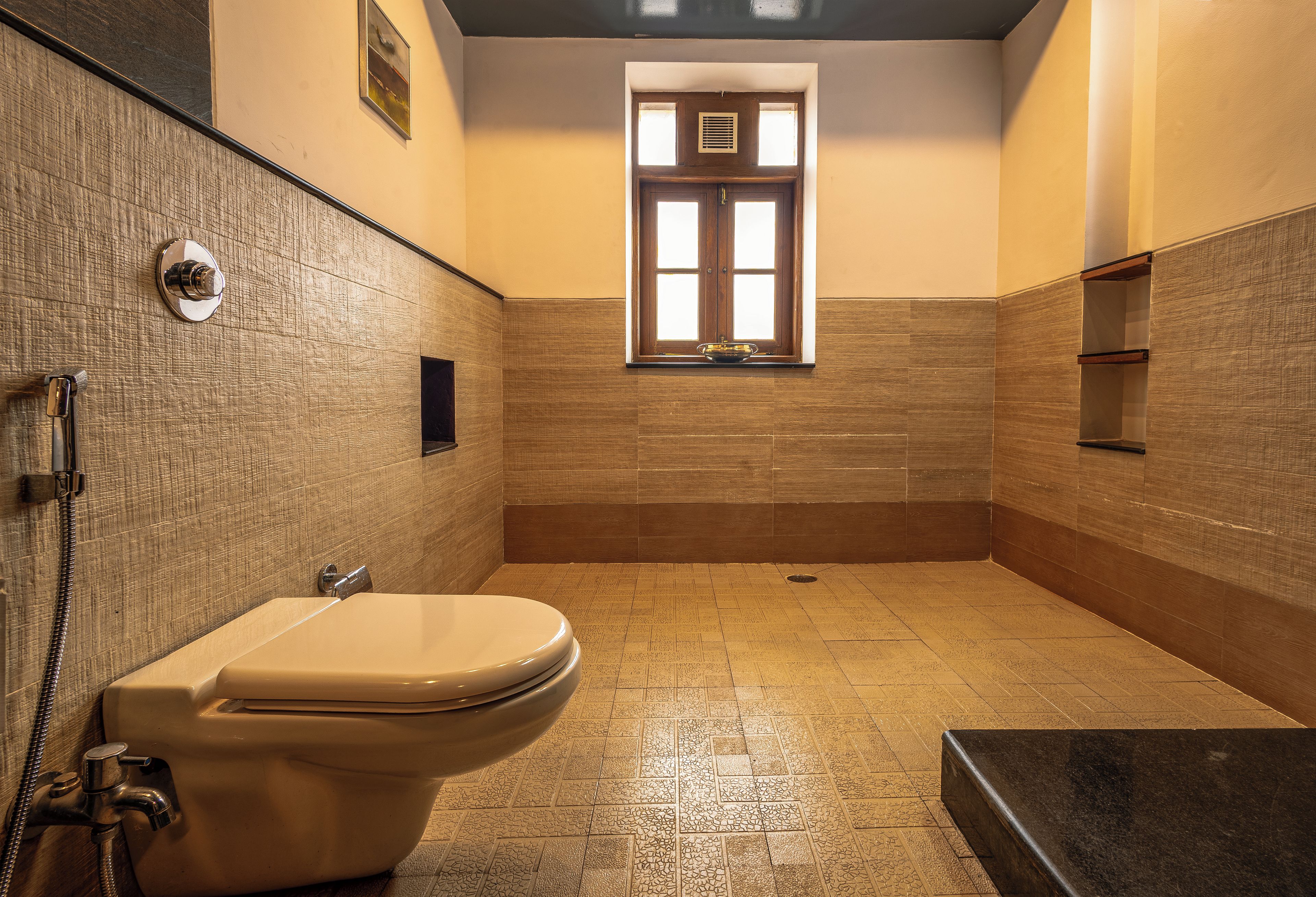 A bathroom with a toilet, a shower, and a window.