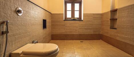 A bathroom with a toilet, a shower, and a window.