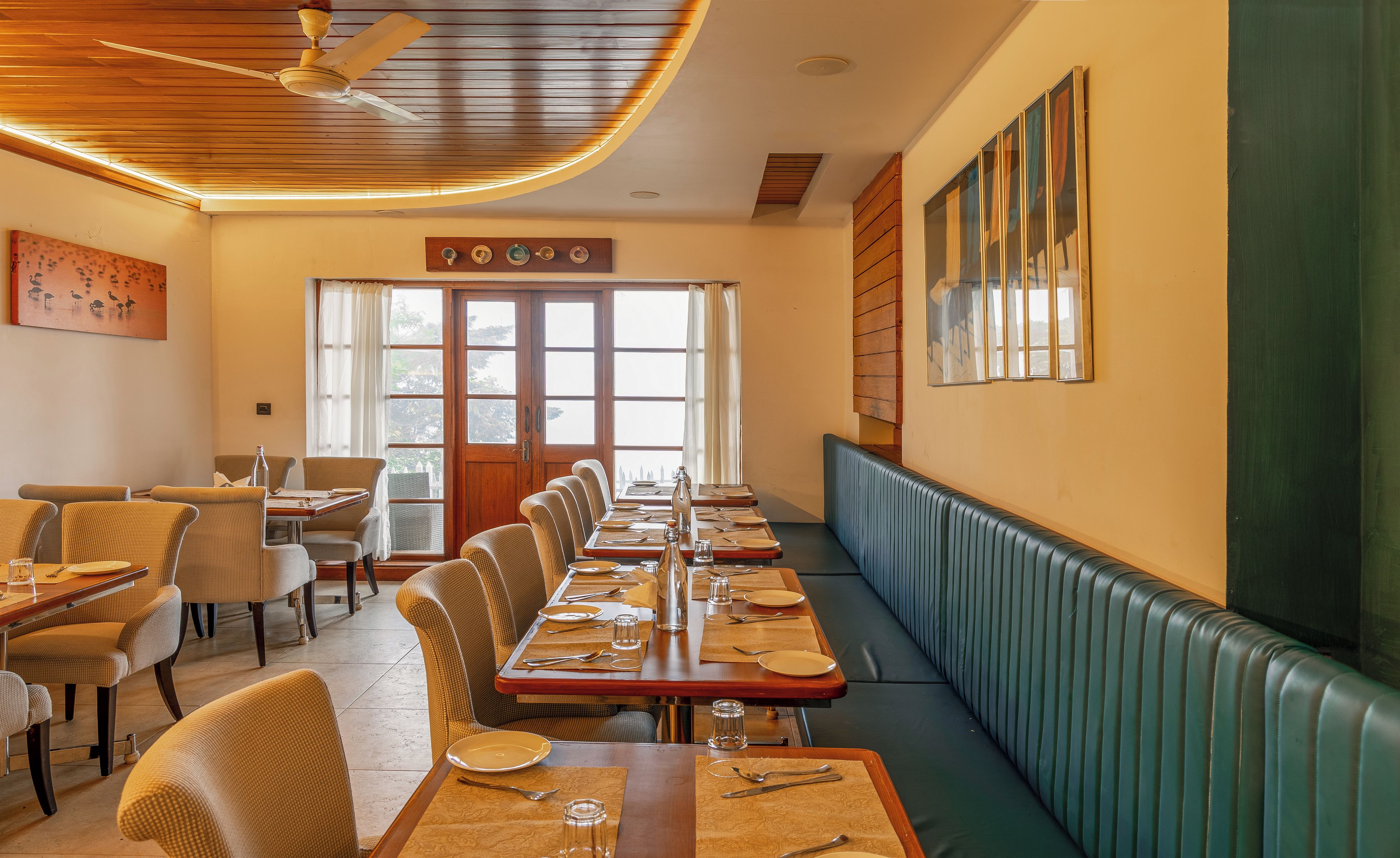 Un restaurante con una larga mesa para comer, cabinas y un techo alto con un ventilador.