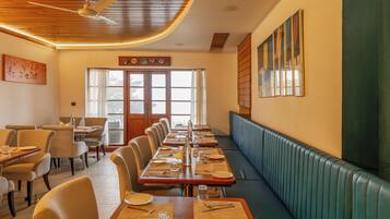 Un restaurante con una larga mesa para comer, cabinas y un techo alto con un ventilador.
