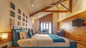 Une chambre d’hôtel avec un grand lit, un bureau, une chaise, une télévision et une fenêtre avec des rideaux.
