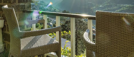 A balcony with wicker furniture overlooking a mountainous landscape.