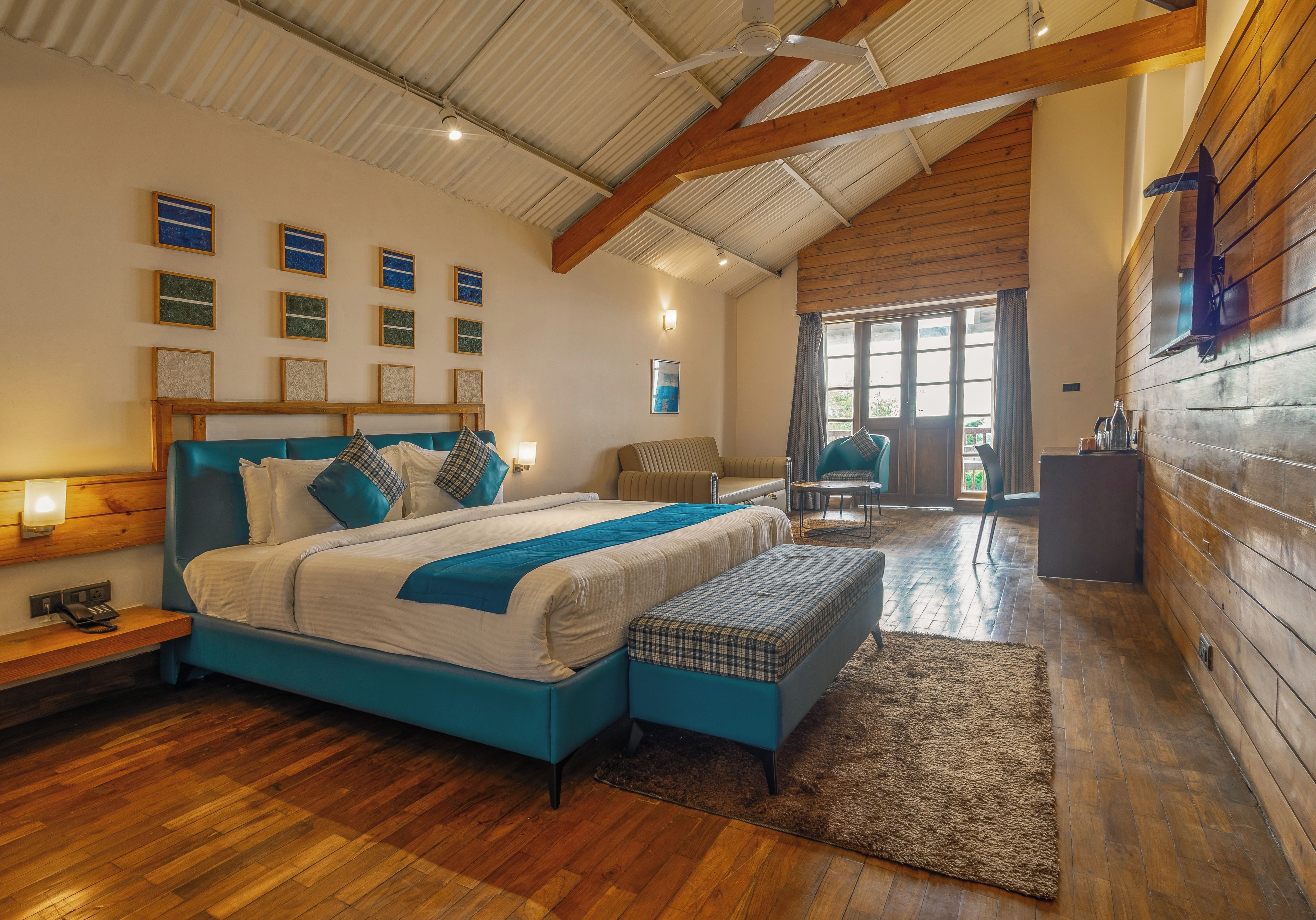 A bedroom with a large bed, a bench, a desk, and a chair.