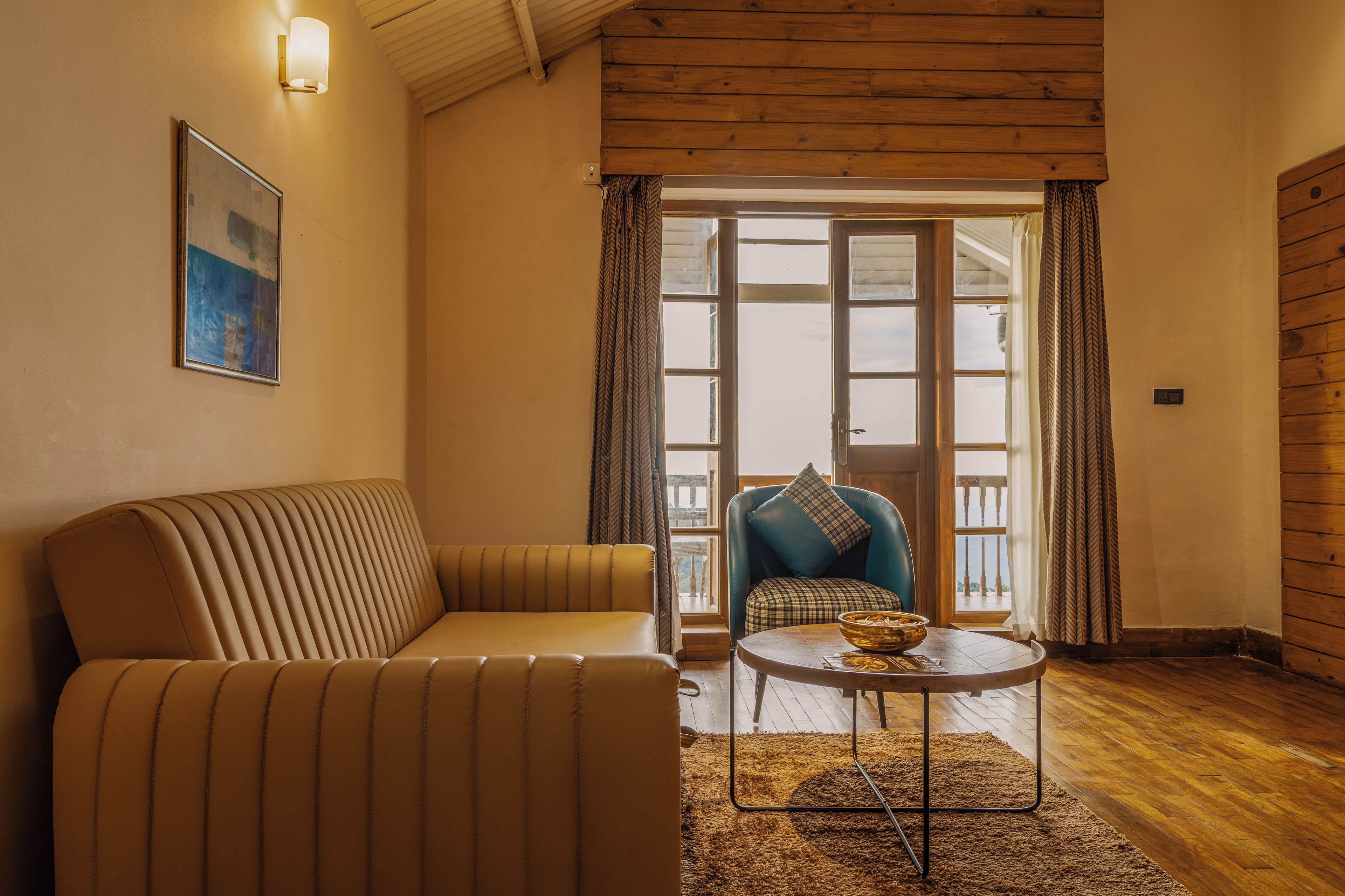 A cozy room with a sofa, a chair, a table, and a view through a window.